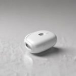 En lille, hvid, oval elektronisk enhed med et digitalt display, der ligger på en lys, struktureret overflade. - Kunstig intelligens AI